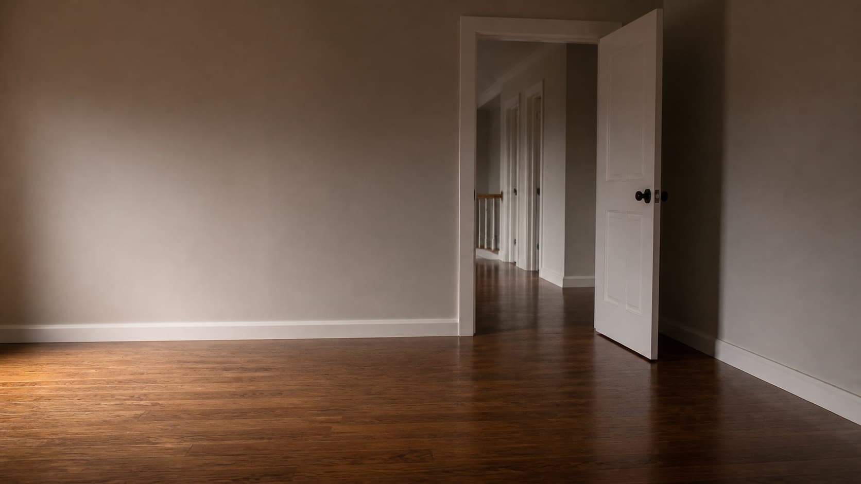 A finished wood floor catching daylight across an empty room